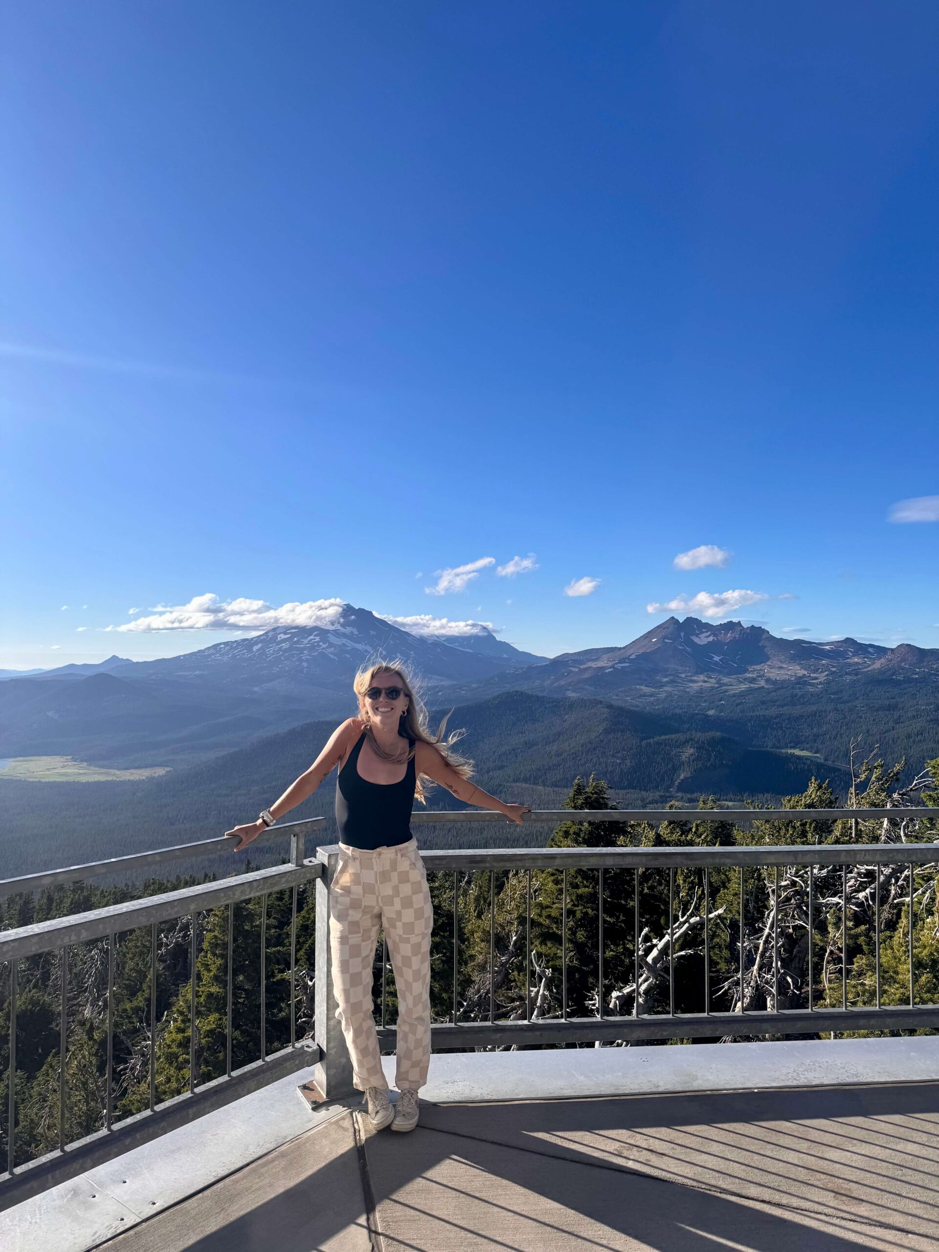 Woman standing infront of mountain landscape smiling with the wind blowing hair.