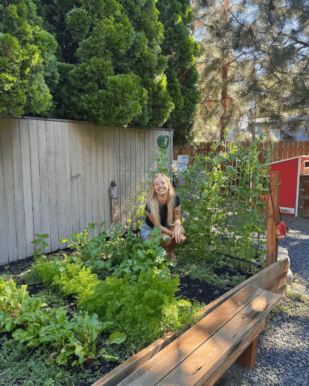 picture of a vegetable garden and woman squatting in the greenery and smiling